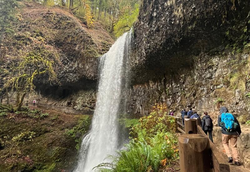 People hiking under a waterfall