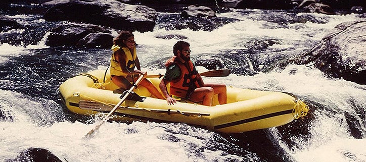 Two people in yellow raft over rapids.