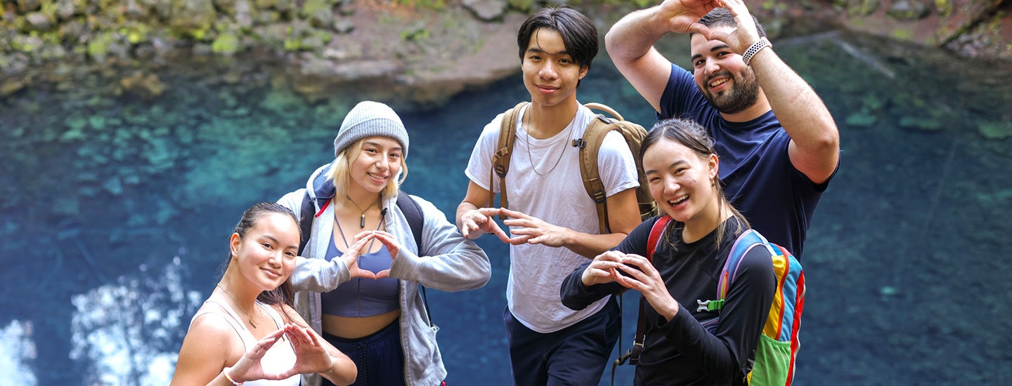 Students stopped on hike by a river giving "o"